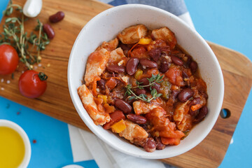 vegetable stew in a white plate on a wooden board close-up. blue background