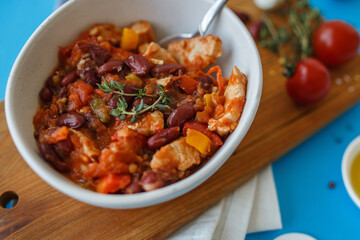vegetable stew in a white plate on a wooden board close-up. blue background