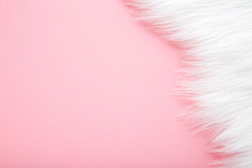Light, white fur on pastel pink table background. Empty place for text. Top down view.