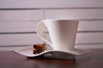 The coffee cup with cinnamon on the brown wodden table