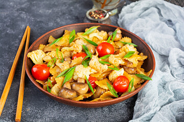 Stir fry farfalle pasta with vegetables, cauliflower and mushrooms