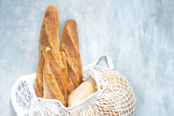 bread, baguette in white string bag on gray background