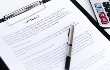 contract, pen and calculator lie on a white background. Business and Finance