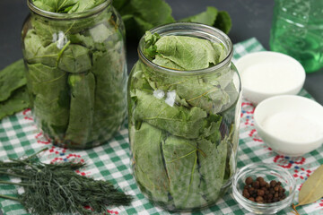 Marinated cucumbers in grape leaves in jars for the winter with garlic and dill, preparatory process closeup