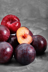 Ripe blue plums lie on a concrete stone background. Natural fruit background with place for text. Copy space. Autumn harvest background.