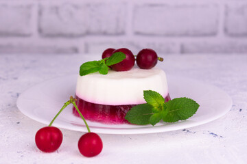 
Panakota with cherry jelly and mint leaves on a white background.