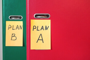 Two folders with stickers, on which plan a or b is written. Business planning. A spare option. Difficulties of enterprise management. Decision making, development options. Background in the blur.
