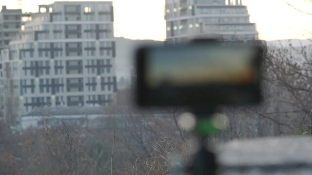 Using mobile phone to record video, capture city scene with video camera app, phone screen closeup rack focus.