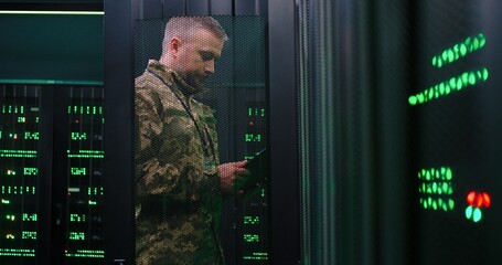 Caucasian army man in camouflage costume opening server and controlling. Male tapping on tablet...