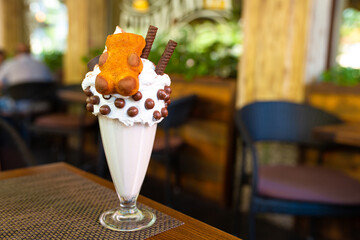 Cool milkshake with cookies and chocolate balls. Milkshake in a glass beaker on a table on a street platform in a cafe. Refreshing summer drinks