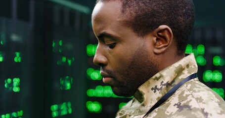 Close up of young African American army technician in camouflage unform standing at servers in...