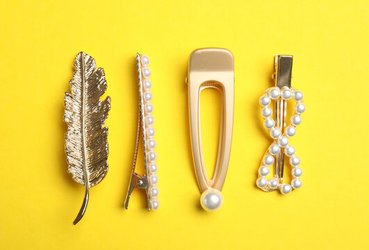 Stylish hair clips on yellow background, flat lay