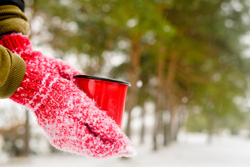 Red mug with hot coffee or tea drink on snow in winter