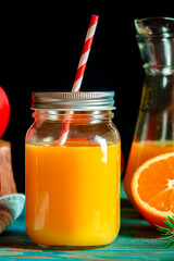 Christmas cocktail. Orange fresh in a glass jar with a tube stands on a wood table next to Christmas toys
