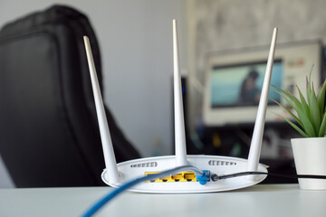 Close up of a wireless router on table at home with desktop computer background