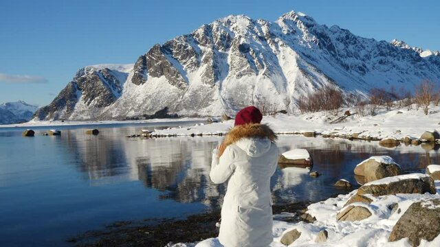 girl taking a photo of sunny winter fjord