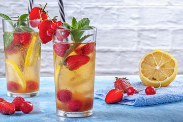 A refreshing summer drink with strawberries, cherries, currants and lemon in glasses on a table