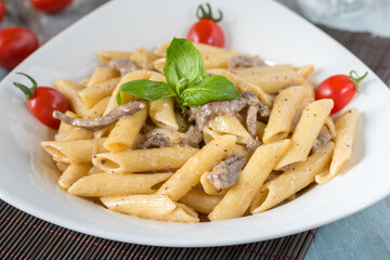 Penne pasta in creamy sauce with chicken, tomatoes decorated with parsley