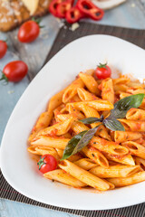 Penne pasta in tomato sauce with chicken, tomatoes decorated with parsley
