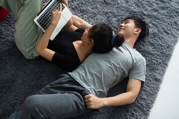 Happy Asian couple spending time together on sofa at home.