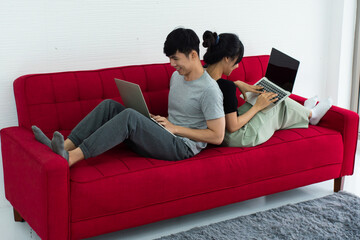Happy Asian couple spending time together on sofa at home.