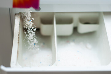 The process of pouring powder into a washing machine