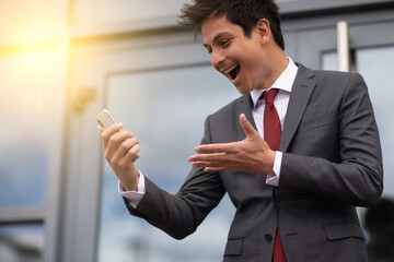 a smiling businessman looking at his cellphone outdoors