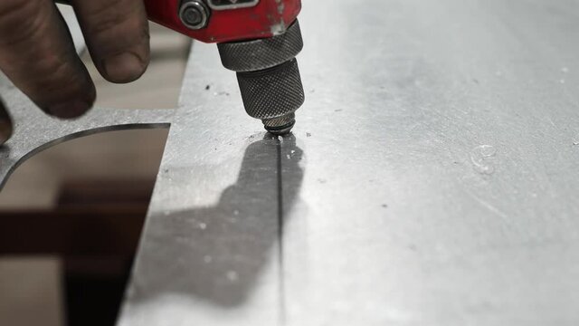 Close up video as male hands are using rivet gun. Sheet of the advertising sheet and man&rsquo;s hands using rivet gun.