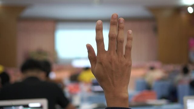 hands of a man in a meeting, Audience raising hand while speaker on stage at conference to answer question while speaker speech at seminar hall with crowd groups in business and education