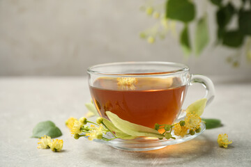 Cup of tea and linden blossom on light grey table