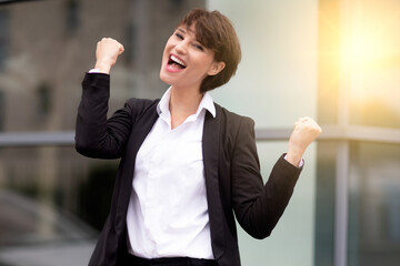 an expressive and happy businesswoman outside