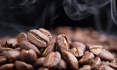 Aroma roasted coffee beans with smoke rising over dark background