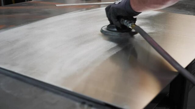 Hand in the glove is buffing a steel sheet. Close up panning video as man&rsquo;s hand is polishing metal sheet.