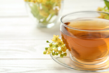 Cup of tea and linden blossom on white wooden table, closeup