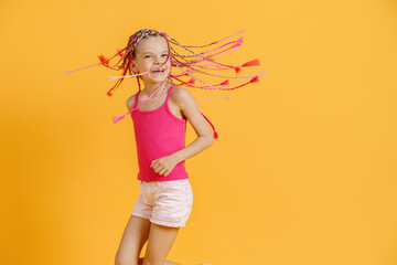 Stylish girl with pink dreadlocks posing in bright clothes on a yellow background. Beauty, fashion.