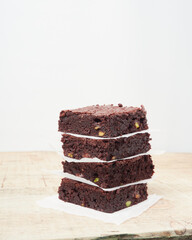 square brownie portions stacked with paper between them on a wooden table with a white background