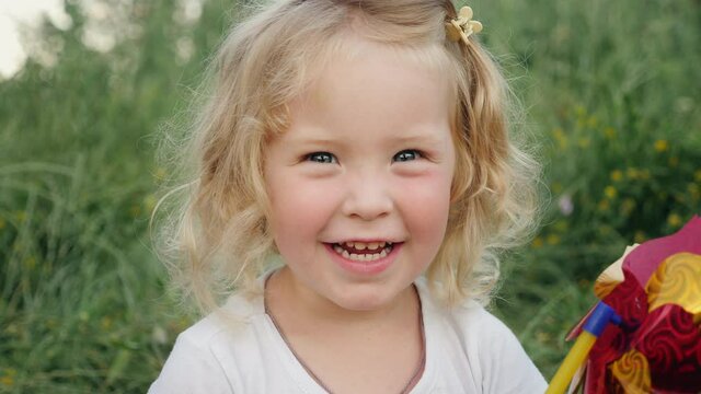 Lovely little girl smiling looking at the camera on nature. Close up little blonde cute girl face.