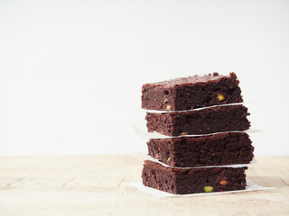 square brownie portions stacked with paper between them on a wooden table with a white background