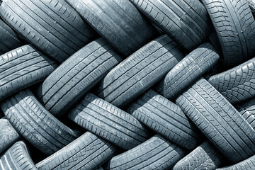 Old used weared car and truck wheels tyres pile stacked in rows stored for recycling. Heap of many rubber tires wall background. Idustrial pollution of environment