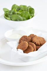 falafel on a white plate with green spinach and sauce