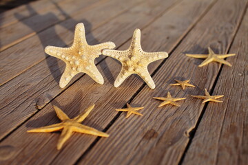 Fototapeta na wymiar Starfish on a wooden pier poured over a wooden deck. Summer vacation concept. Holidays by the sea