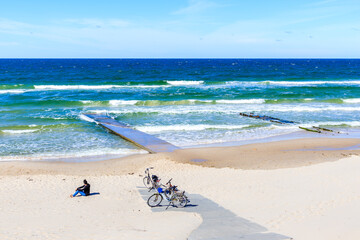 Woman tourist sitting on beautiful white sand beach near Kolobrzeg, Baltic Sea coast, Poland