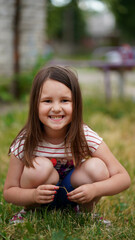 Portrait of cute little girl squatting on grass in summer