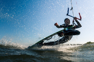 Kitesurfer doing an impressive darkslide trick with lots of spray water