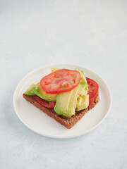 bread toast with avocado and tomato slices on a plate