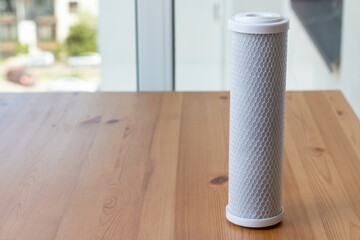 Filter cartridge for drinking water purification for on a wooden table against a blurred...