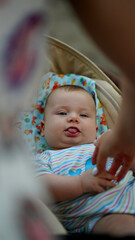 Little baby with sticking out tongue lying in a stroller