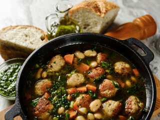 Cooking homemade soup with meatballs cutlets and vegetables in big pot on home kitchen background with ingredients. Copy space, closeup. Healthy food recipe book concept