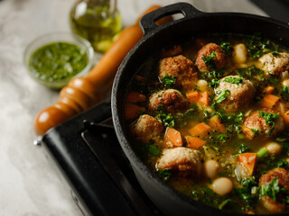 Cooking soup with meatballs cutlets and vegetables in big pan pot on home kitchen background by chef hands. Copy space, closeup. Homemade food recipe concept.
