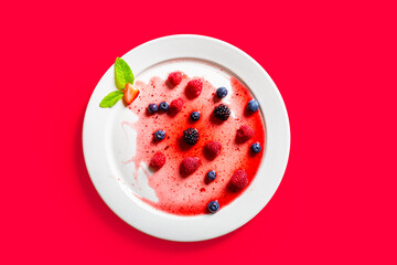 Strawberries and blackberries on defrosted popsicle over a red background